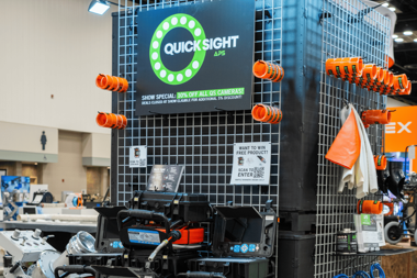 Quick Sight sewer inspection camera display featuring pipe inspection cameras and accessories at a trenchless industry trade show.